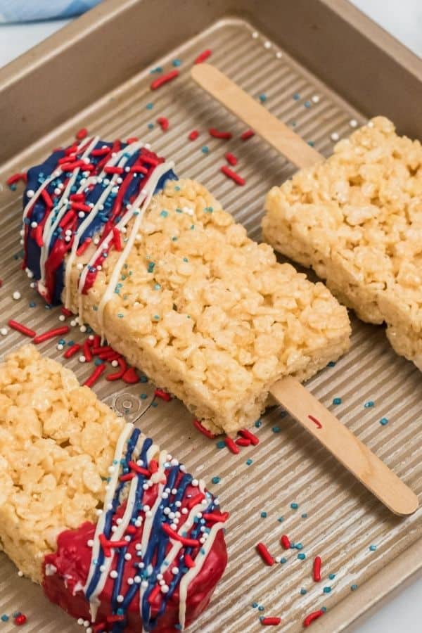 Close up of dipped rice krispy pops with drizzles of red white and blue chocolate.