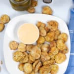 White plate of fried pickles with dipping sauce.