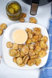 White plate of fried pickles with dipping sauce.