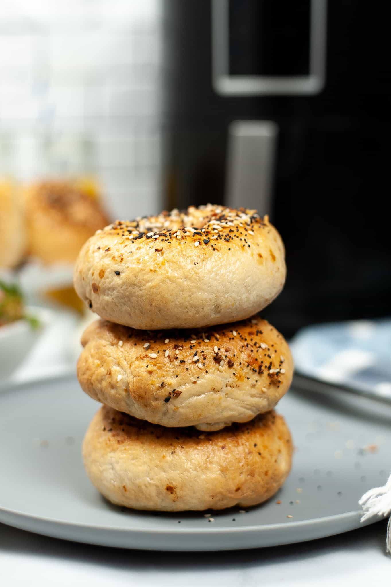A stack of 3 air fryer everything bagels on a grey p;are