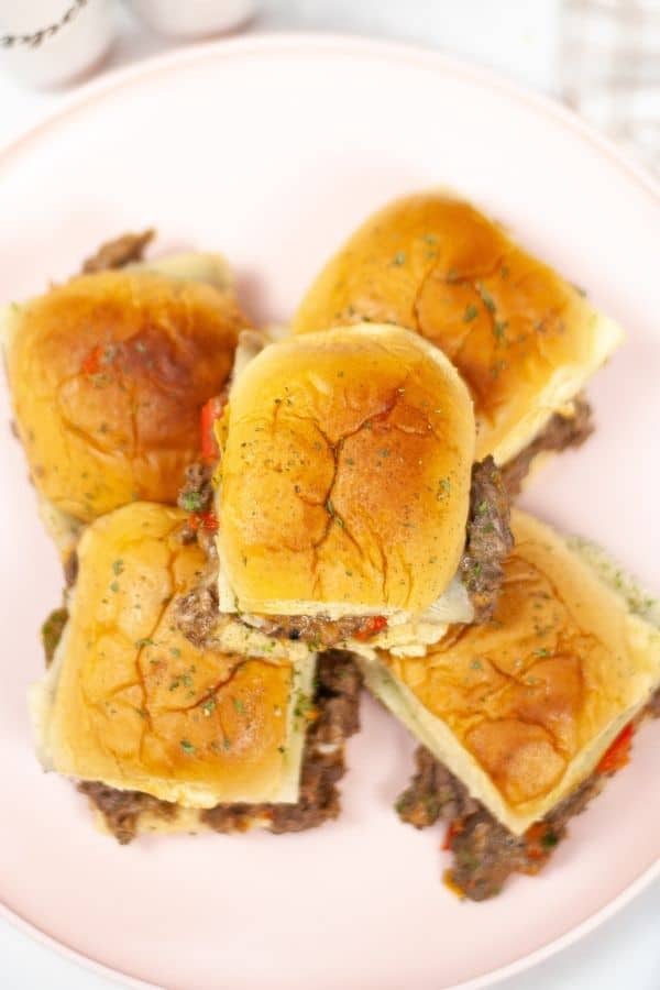 Top shot of a plate of instant pot cheesesteak sliders on a white plate.