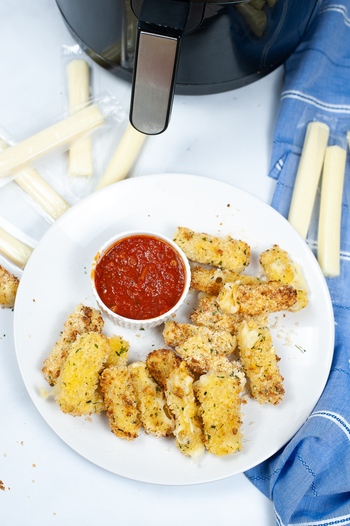 Shot looking from the top of a  plate of air fried mozzarella sticks with marinara sauce.