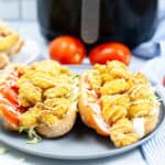 Two Shrimp Po Boy Sandwiches on a blue plate with an Air Fryer in the background.