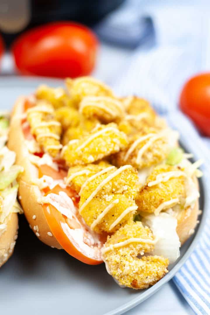 Close up on a Shrimp Po Boy Sandwich with cherry tomatoes in the background.