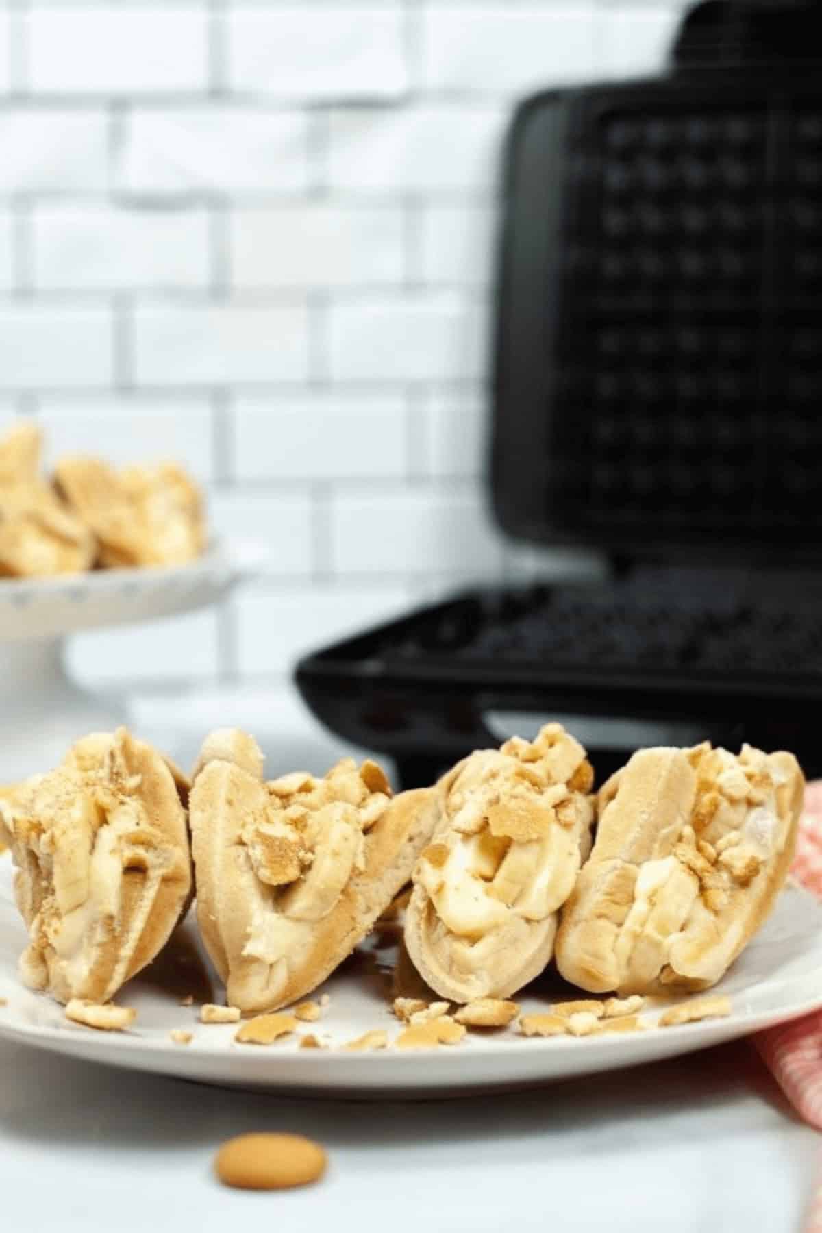 A closeup of a plate of banana tacos next to a waffle iron.