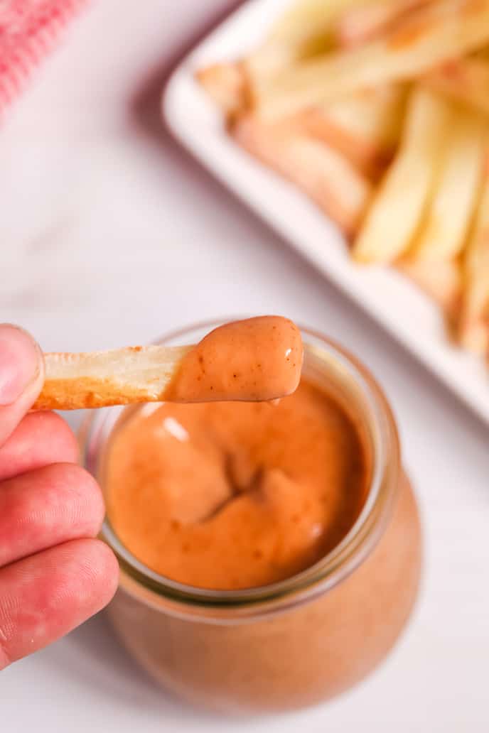 French fry dipped in Campfire sauce recipe with french fries in the background