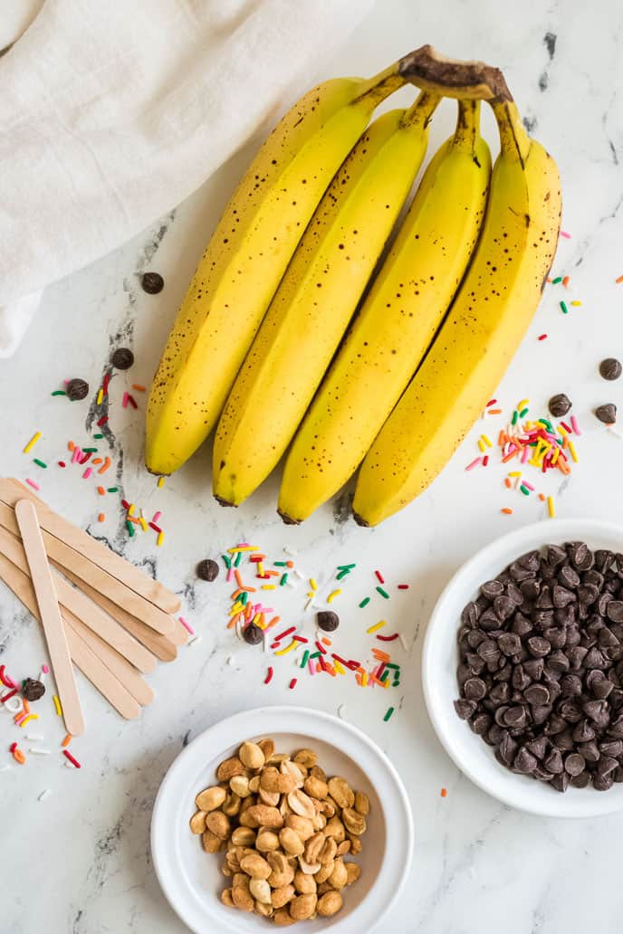 A bunch of bananas, chocolate, sprinkles and sticks.