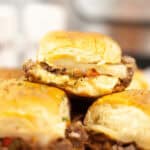 Close-up of stacked sandwich with melted cheese and seasoned filling, placed on a pink plate, soft background focus.