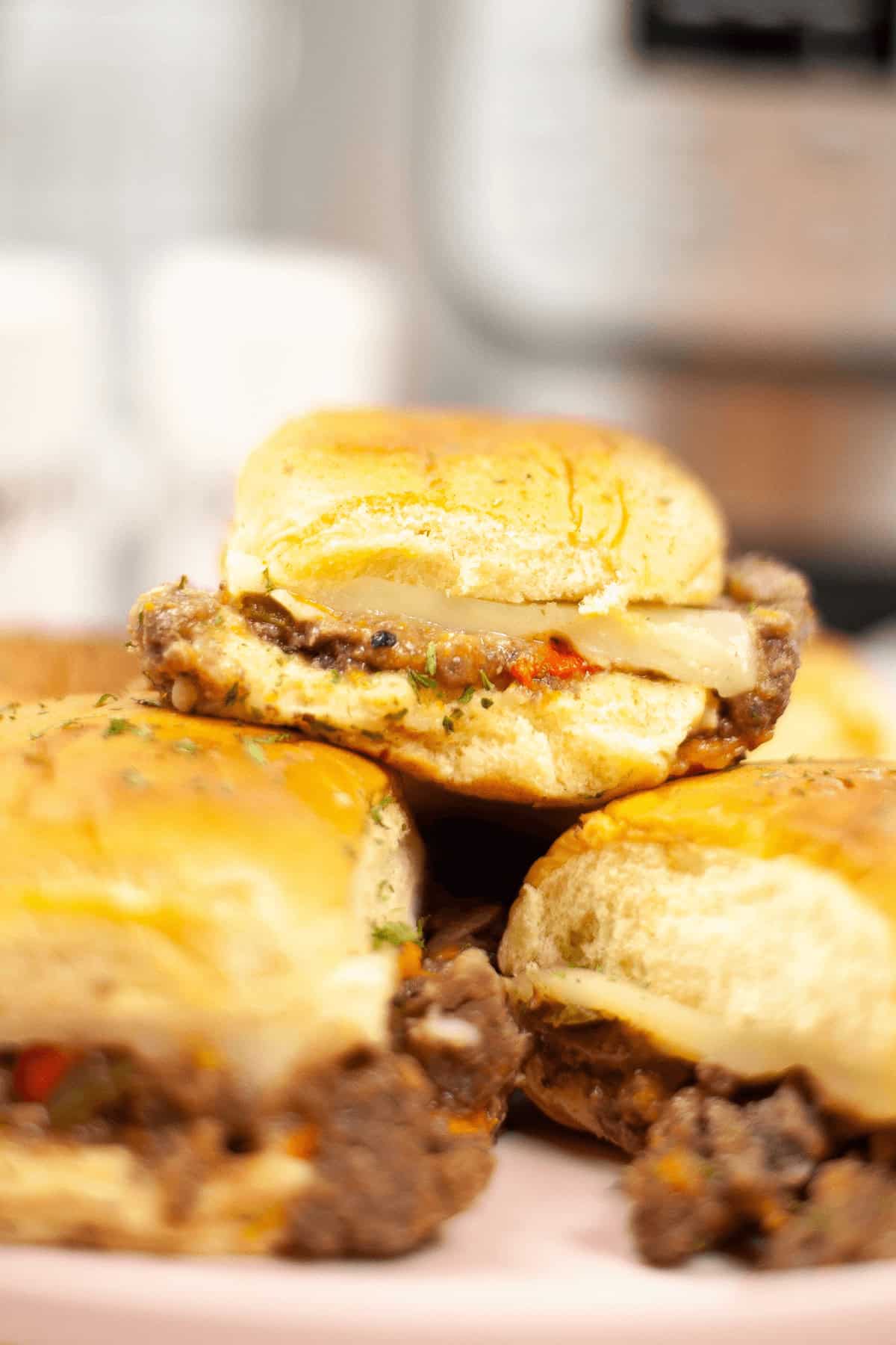 Close-up of stacked sandwich with melted cheese and seasoned filling, placed on a pink plate, soft background focus.
