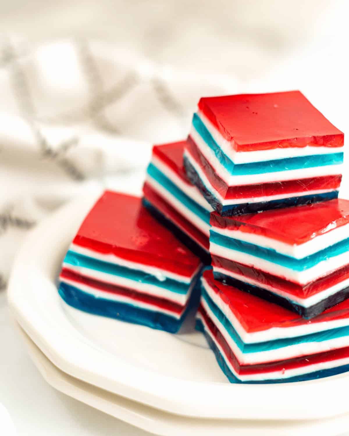A plate of desserts with red, white, and blue stripes is shown, placed on a white surface with a blurred background.