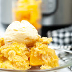 Close up side view of peach cobbler topped with ice cream.