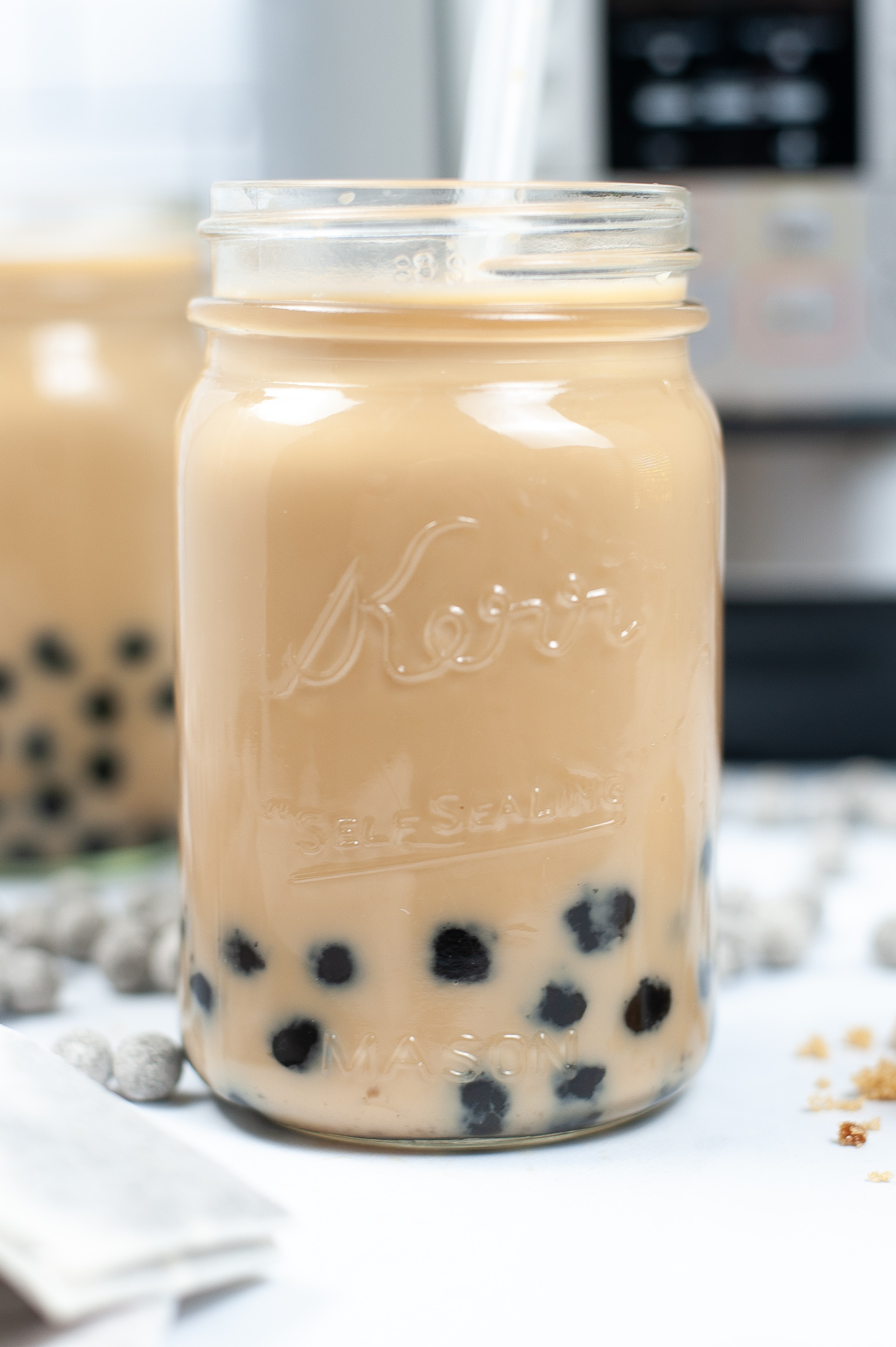 Side view of a mason jar filled with bubble tea with a straw.