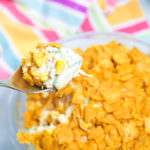 A spoonful of frito corn dip with a multi colred striped napkin in the background.