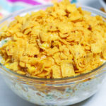 side view of frito corn salad in a clear glass bowl.