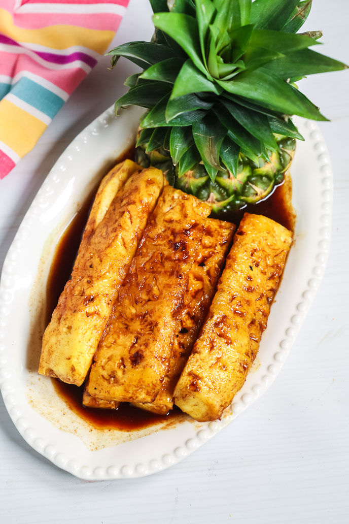 Grilled brazilian pineapple on a white plate with a striped napkin
