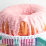A blue and pink stripped napkin with a cake stand on it with a cherry limeade cake in the bundt style.
