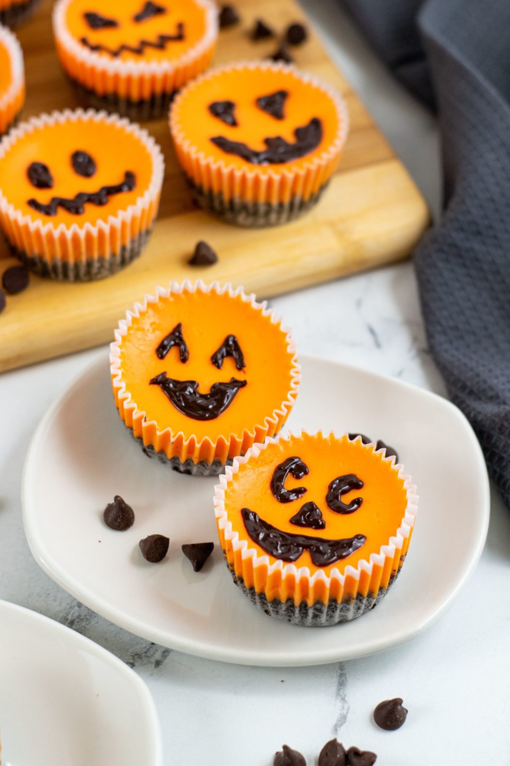 Mini Halloween Cheesecakes on a white plate with jack o lantern faces.