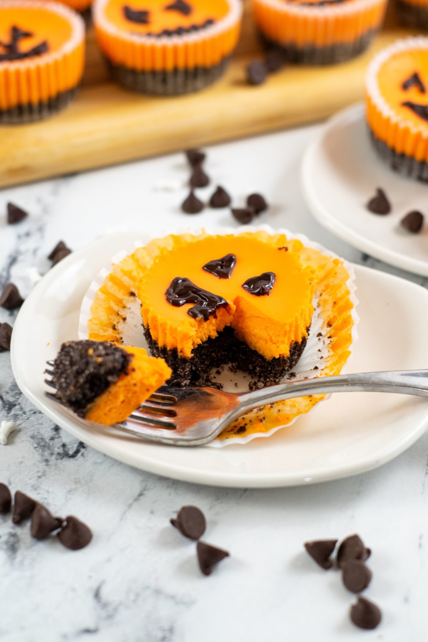 A white dish with a mini Halloween cheesecake on the plate with a fork full on the side.