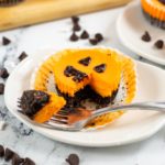 A white dish with a mini Halloween cheesecake on the plate with a fork full on the side.
