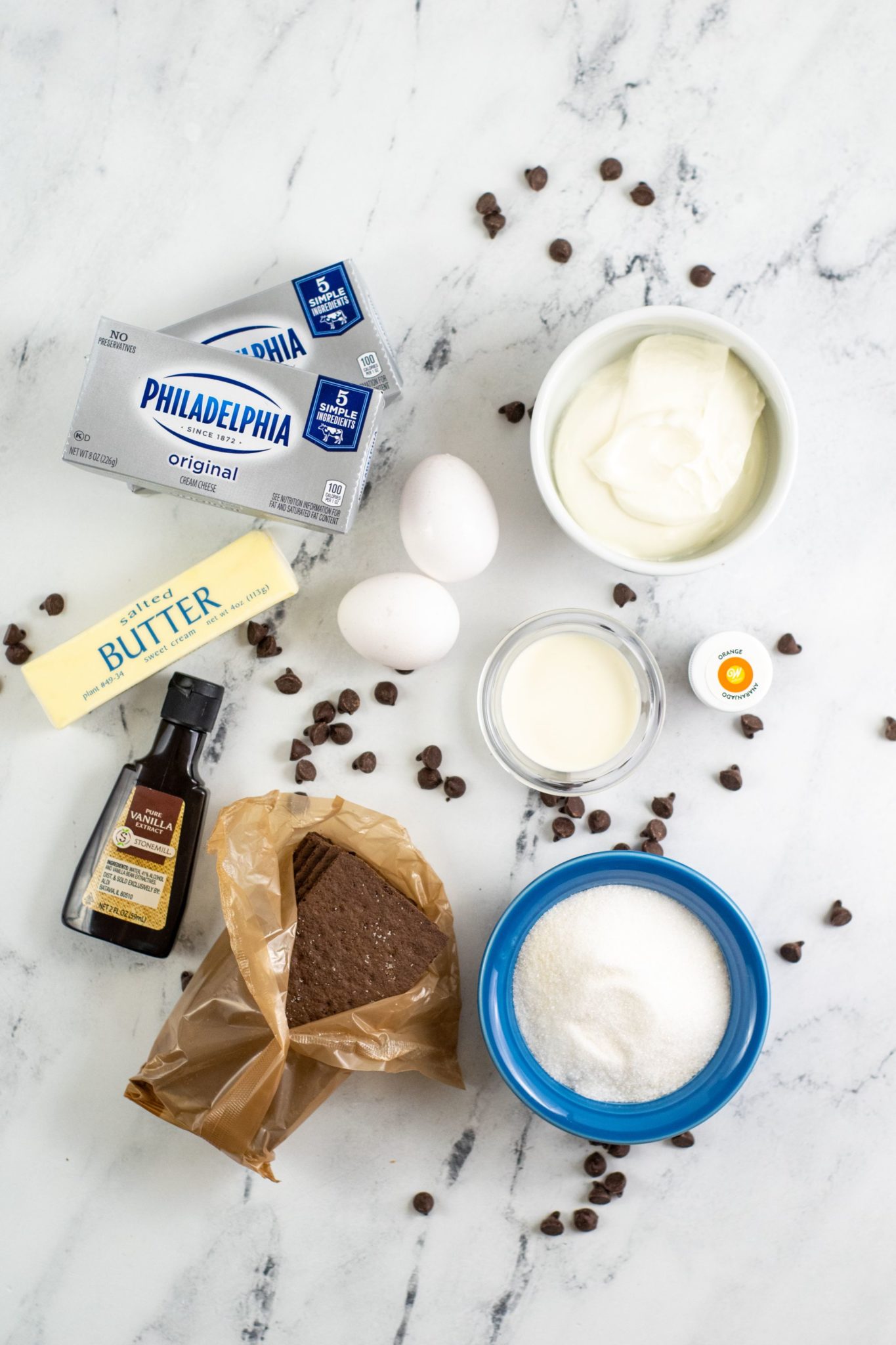 Butter, cream cheese, eggs, vanilla, flour and other ingredients needed to make cheesecake.