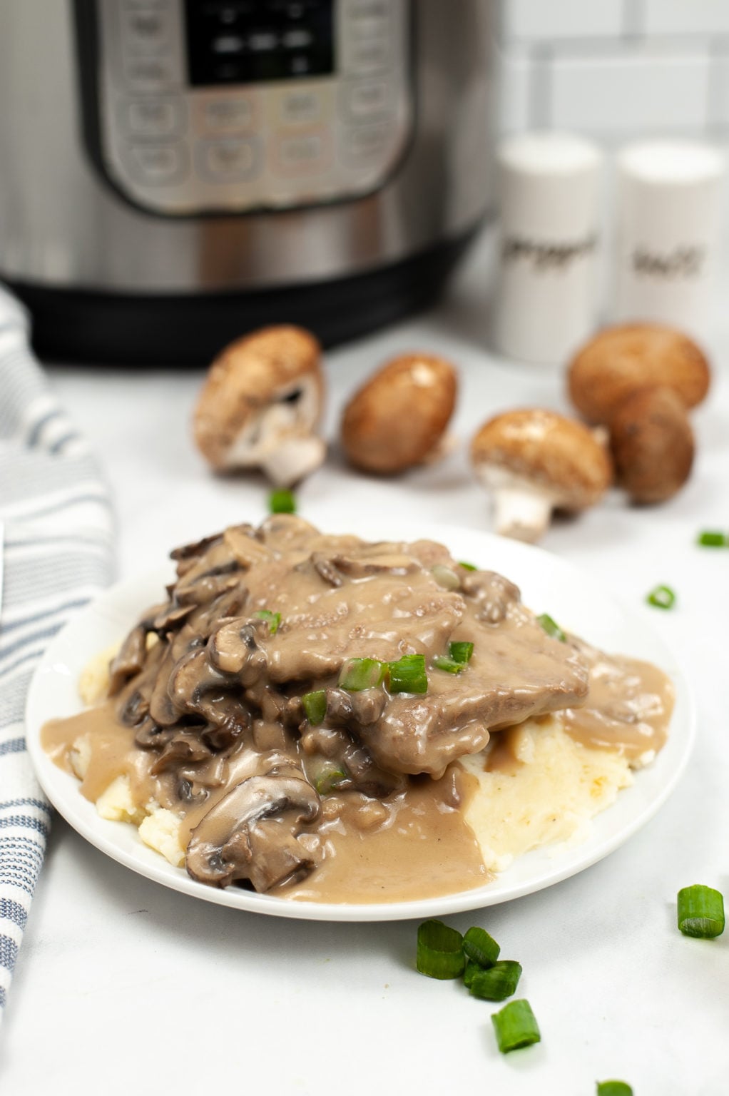White plate of salisbury steak with the Instant Pot in the background.