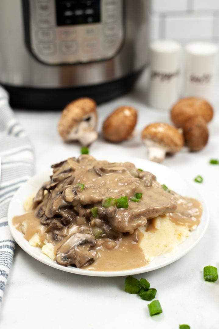 White plate of salisbury steak with the Instant Pot in the background.