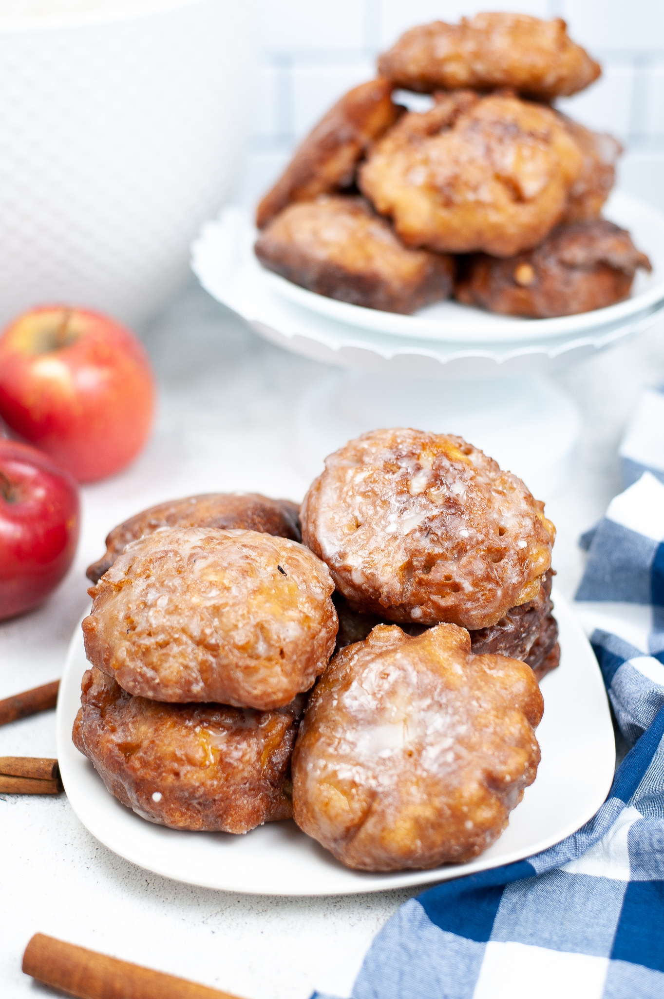 White dish of apple fritters with apples in the background.