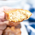 An apple fritter with a bite taken out in close up.