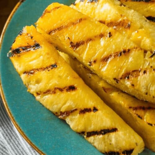Grilled pineapple slices on a blue plate, displaying perfect grill marks and a golden-brown char.