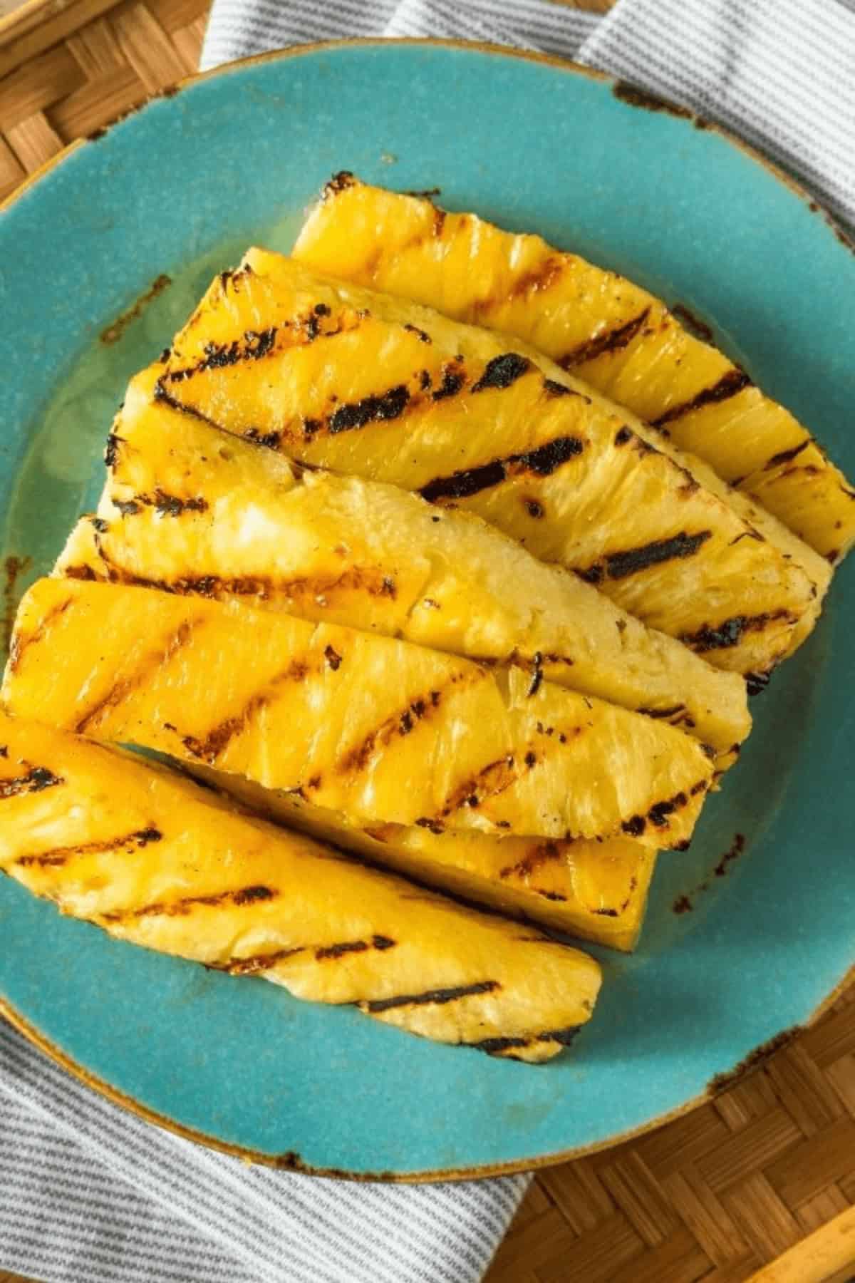 Grilled Pineapple Slices with perfect char marks are artfully arranged on a vibrant blue plate.