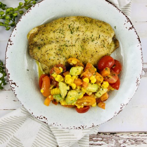 Oven Baked Haddock with Corn Salad on a scalloped plate.