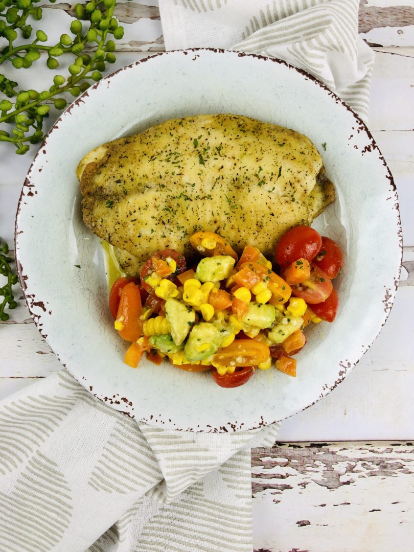 Oven Baked Haddock with Corn Salad on a scalloped plate.