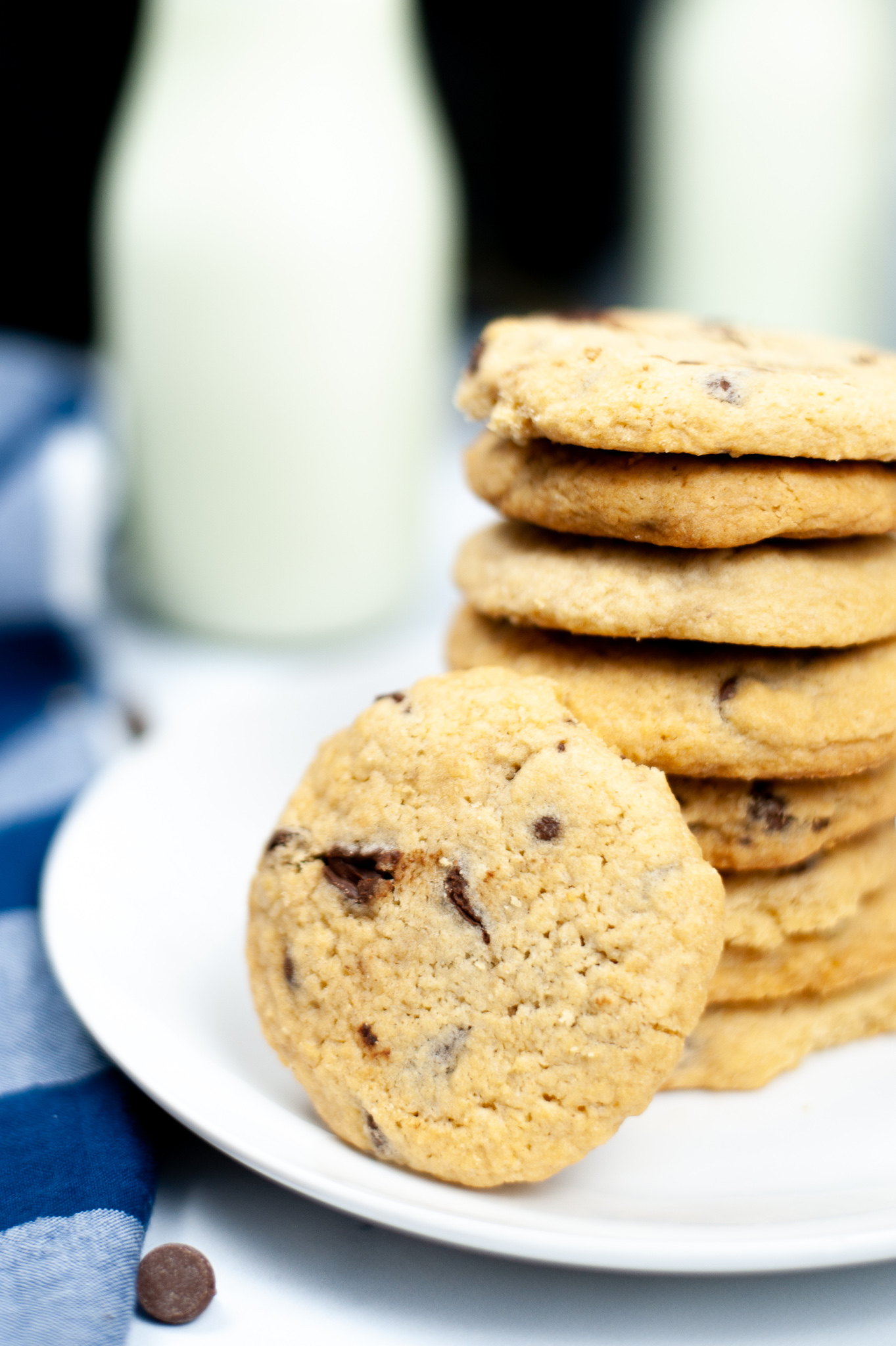 Air Fryer Chocolate Chip Cookies stacked on a plate with one cookie on the side with a container of milk.