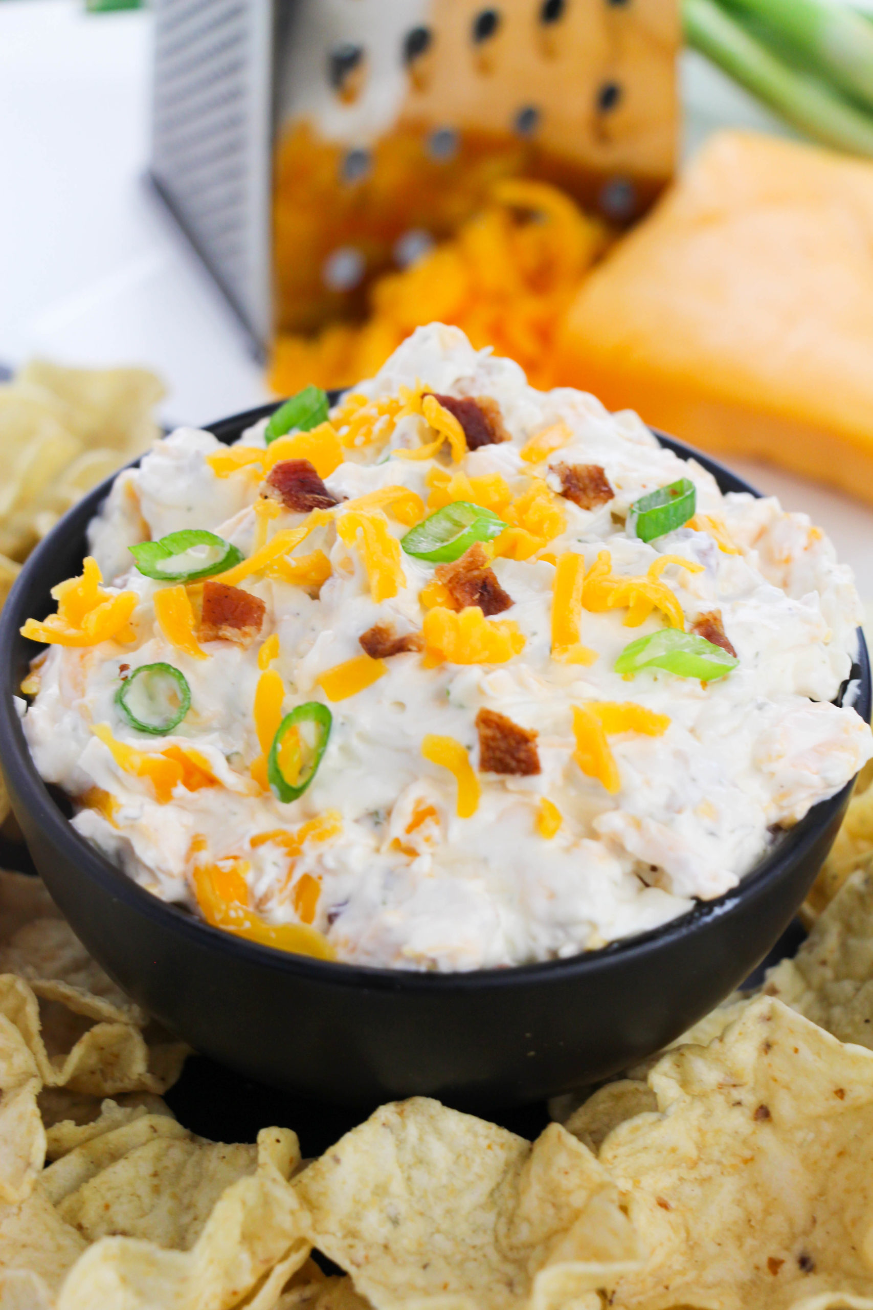 Bacon Ranch Dip pictured from the side top of this dish surrounded by chips.