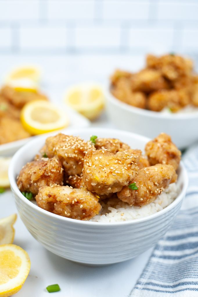 white bowl filled with rice and topped with Lemon Chiicken.
