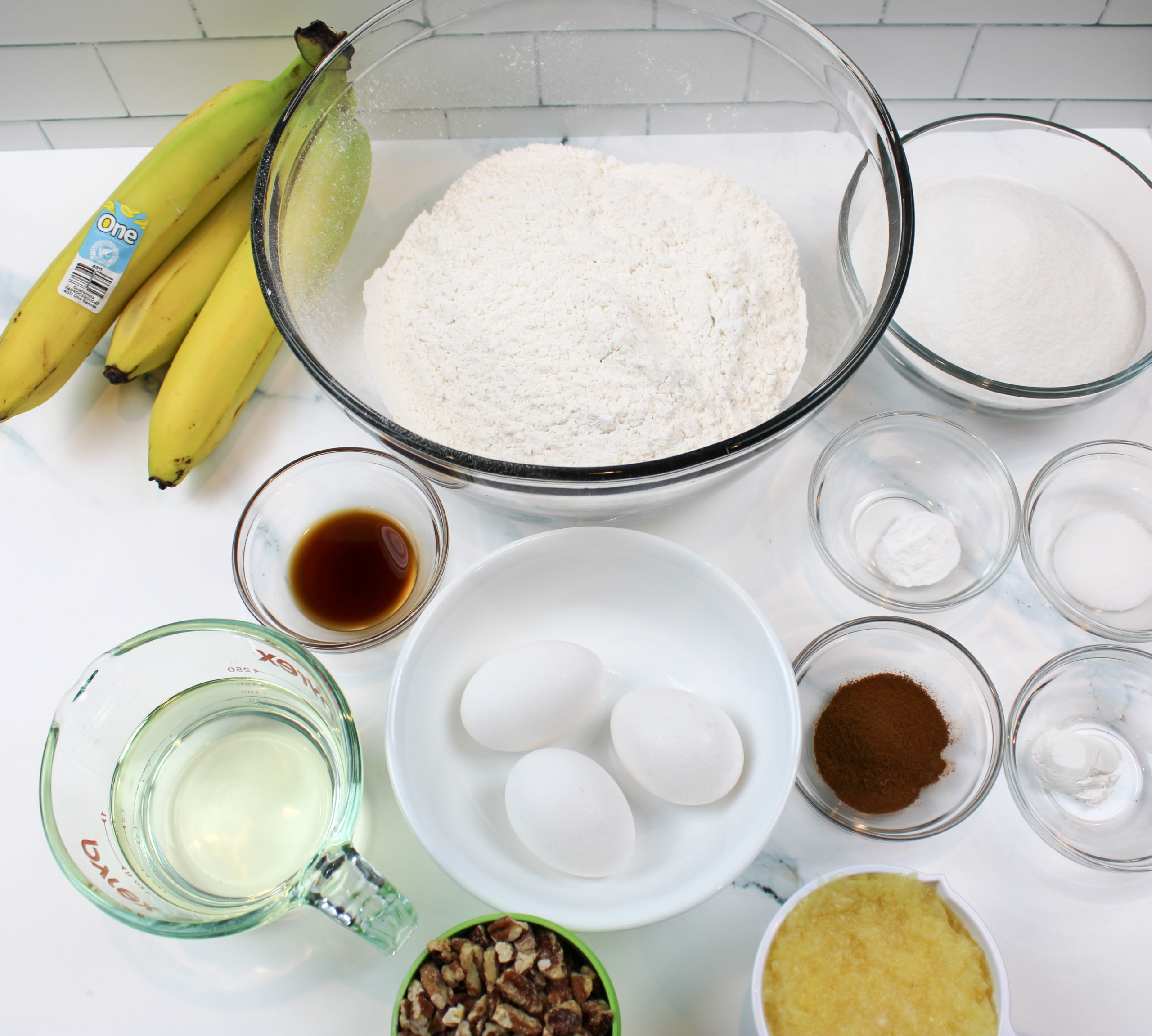 Bowl of flour, eggs pineapple, seasonings and bananas.