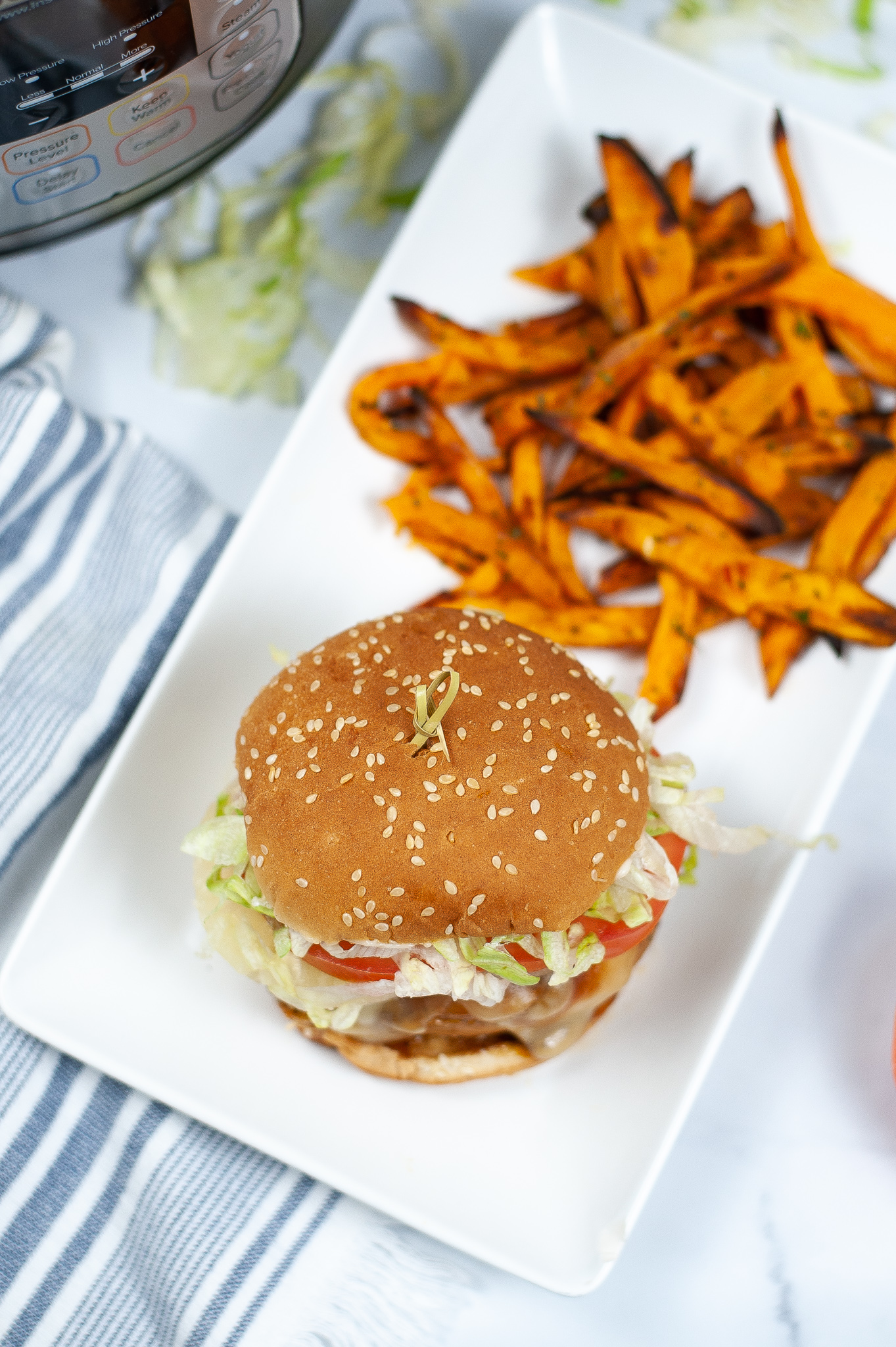 A square dish with the teriyaki chicken sandwich with a side of sweet potato fries.