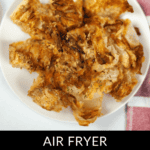 A plate of crispy Air Fryer Blooming Onion sits invitingly, accompanied by a striped napkin on the side.