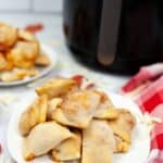 A plate of crispy appetizer rests on the countertop, showcasing a deliciously golden brown finish. Nearby, a red checkered cloth peeks into view from the right side.