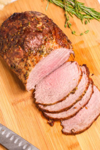 Beef eye of round roast sliced on a cutting board