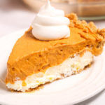 Double-Layer-Pumpkin-Pie on a white plate topped with whipped cream.
