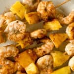 Hawaiian Garlic Shrimp Skewers and pineapple served on a light-colored plate.