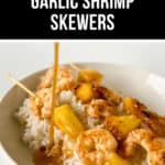 A plate of rice topped with Hawaiian Garlic Shrimp Skewers and pineapple chunks, with sauce being poured over the dish. The title "Hawaiian Garlic Shrimp Skewers" is displayed at the top.