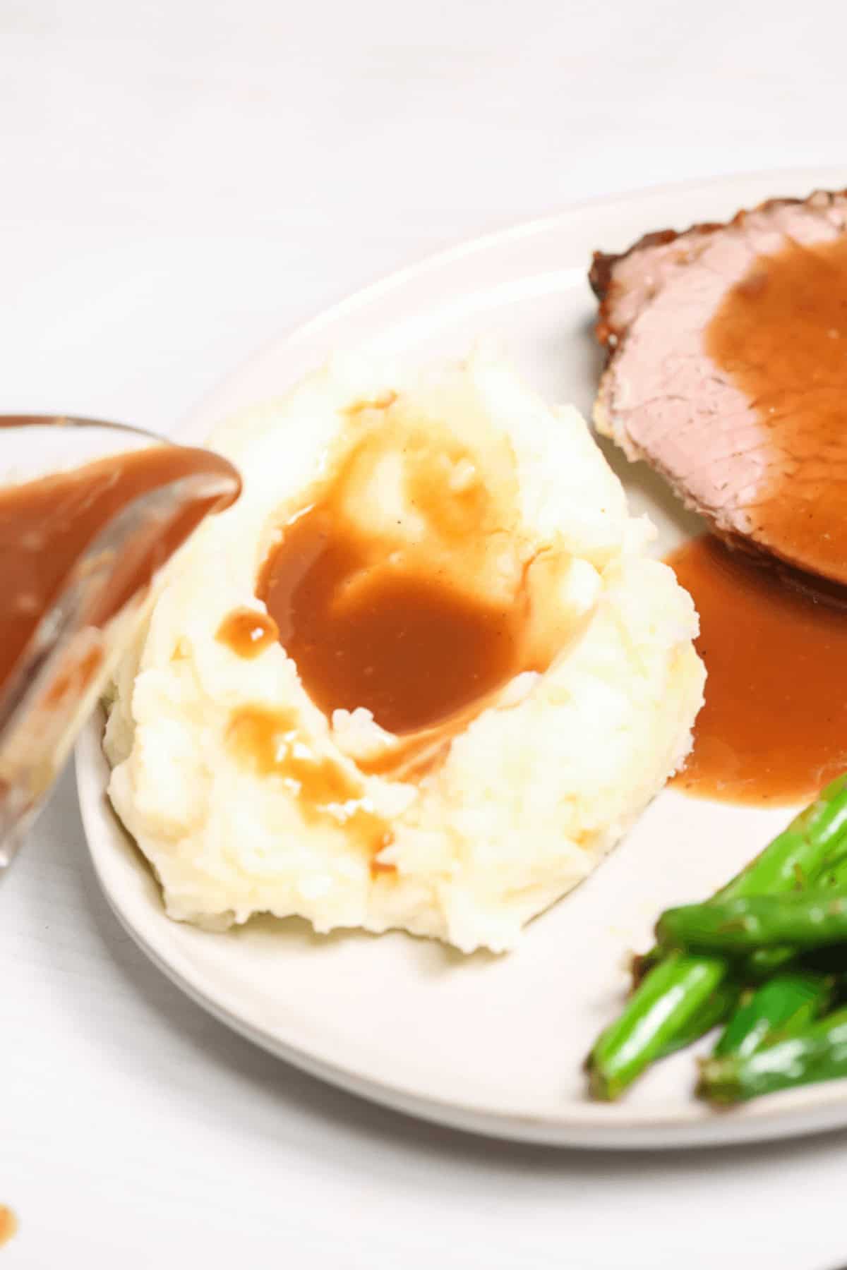 A side view of the brown gravy on top of mashed potatoes and beef.