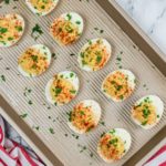 Hummus Deviled Eggs on a tray. sprinkled with herbs.