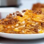 A plate of instant pot lasagna on a table next to an Instant Pot, ready to be served.