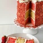 A tall layered cake with pink and yellow sponge, white frosting, and strawberries on top—just like a classic Cake Recipe.