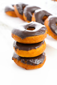 A stack of three chocolate glazed biscuit donuts.
