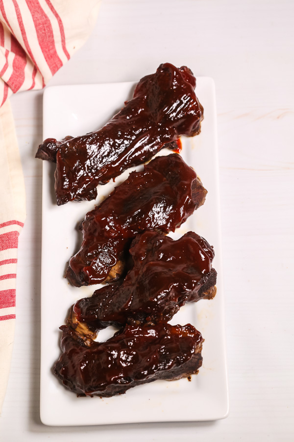 Country style beef ribs with BBQ sauce on a white plate. 