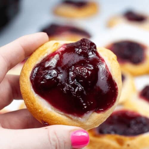 A hand holding an air fryer cherry danish.